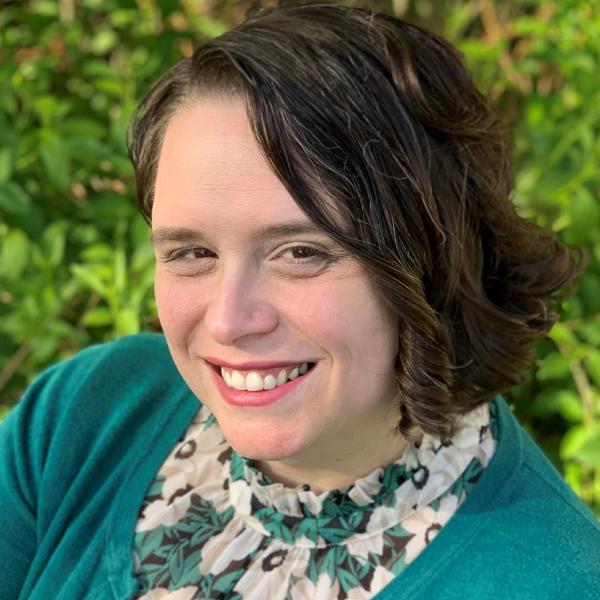 Woman with short brown hair, floral shirt, and turquoise sweater