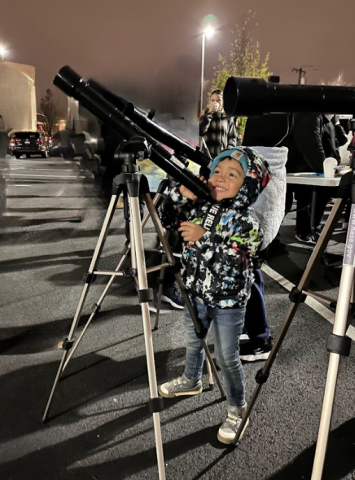 Little boy looks at the sky through a telescope